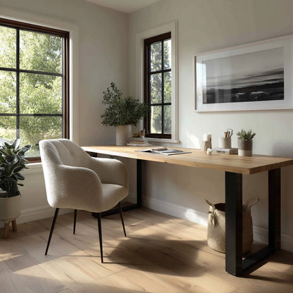 Modern home office with a wooden desk, chair, and framed artwork.