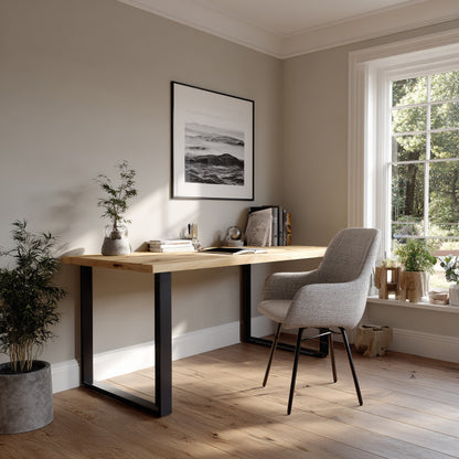 Modern home office with wooden desk, chair, and framed artwork on a light gray wall.