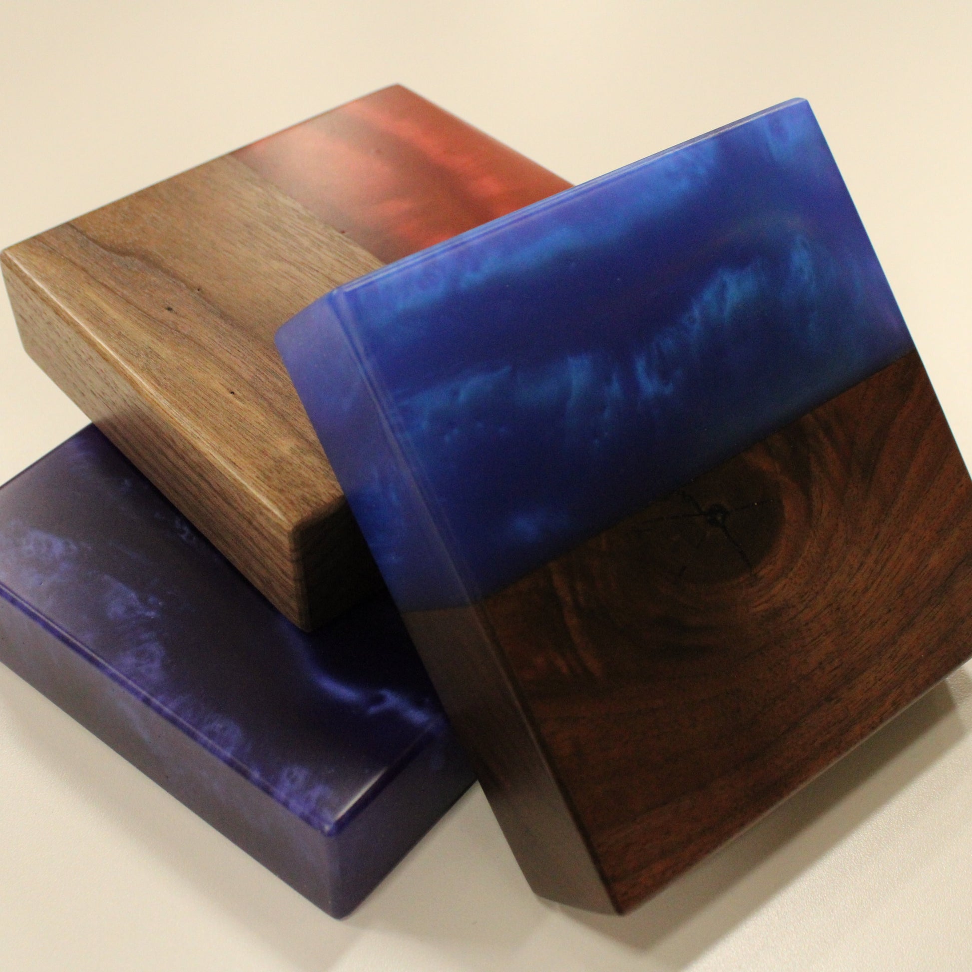 A set of three wooden blocks with epoxy samples in red, blue, and purple colors, displayed on a white background.
