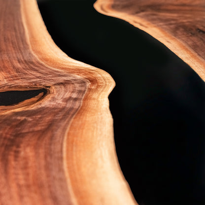 Close-up of a live-edge wooden surface with rich warm brown grain and a dark recessed channel running through the center.