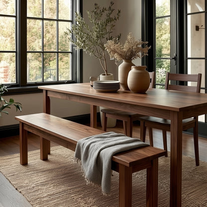 Wooden dining table with chairs and a bench in a room with large windows.