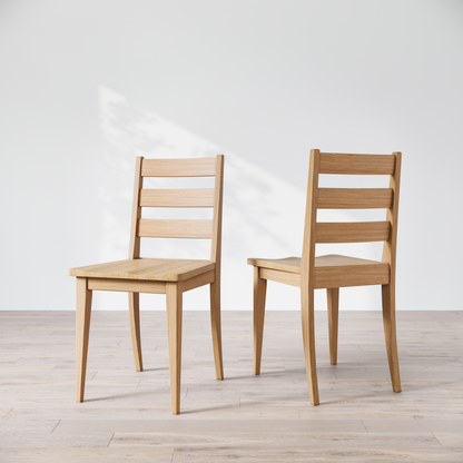 Two wooden dining chairs featuring a simple, solid backrest and seat design on a light background.