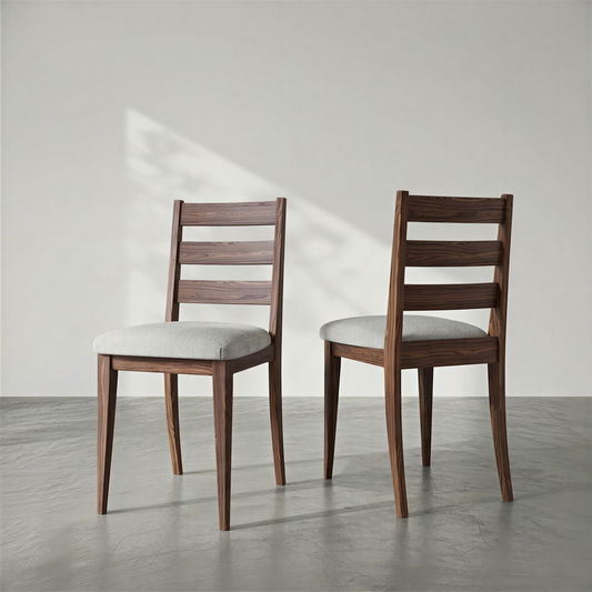 Two wooden chairs with white cushions on a gray floor and light gray wall.