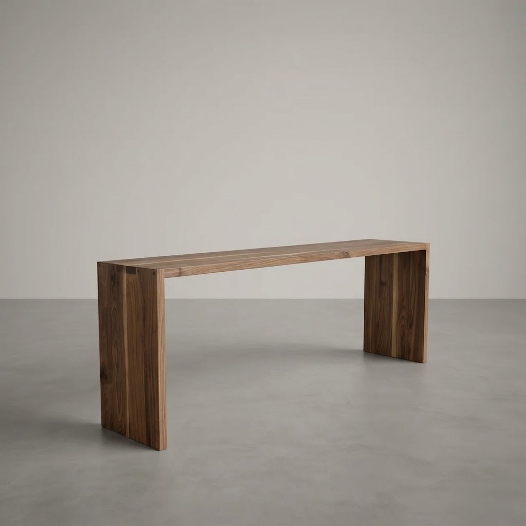 A minimalist wooden console table with a rectangular top and two thick block legs, shown in a clean studio setting with a neutral gray floor and background.
