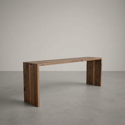 A minimalist wooden console table with a rectangular top and two thick block legs, shown in a clean studio setting with a neutral gray floor and background.