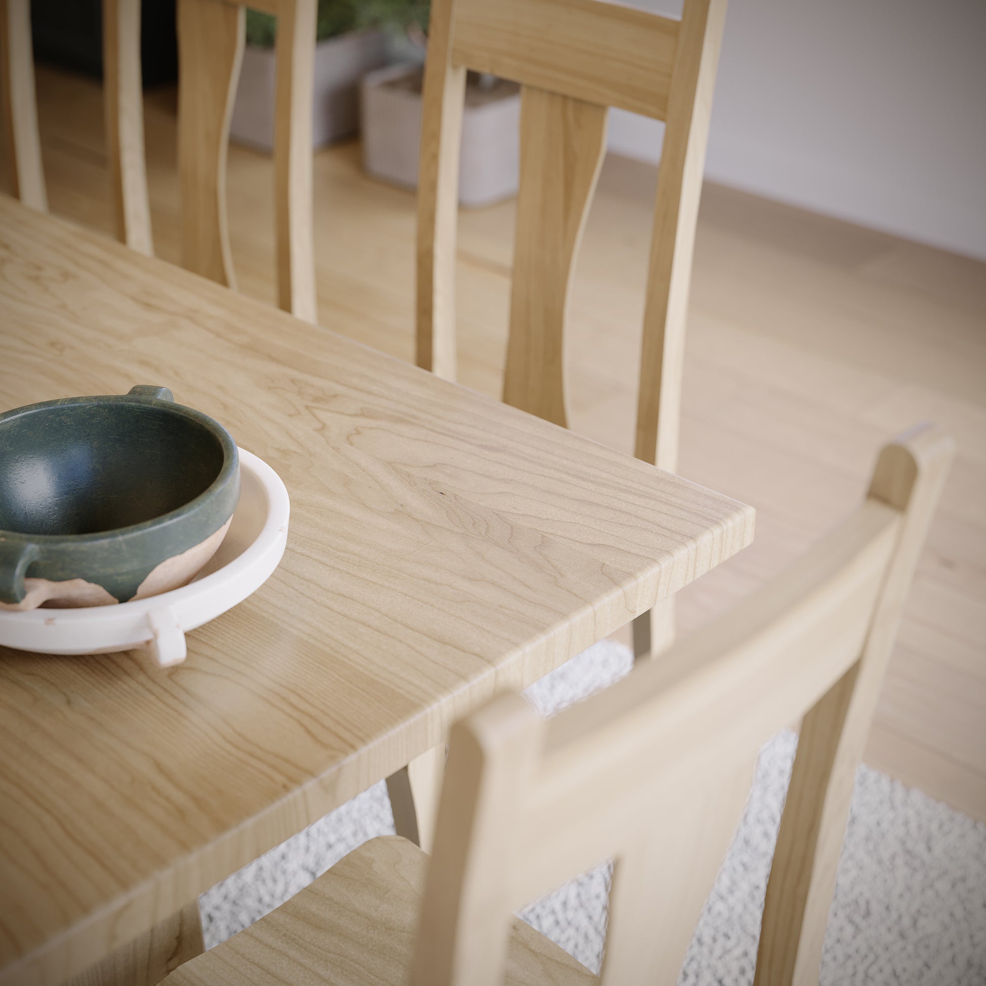 Wooden table with a green ceramic bowl and white coaster.