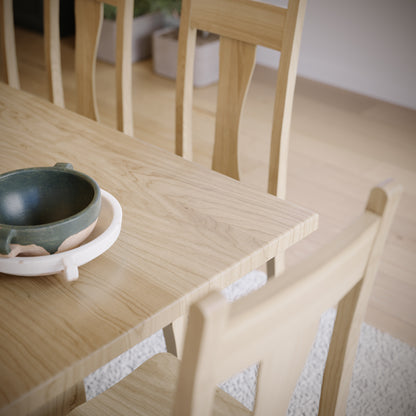 Wooden table with a green ceramic bowl and white coaster.
