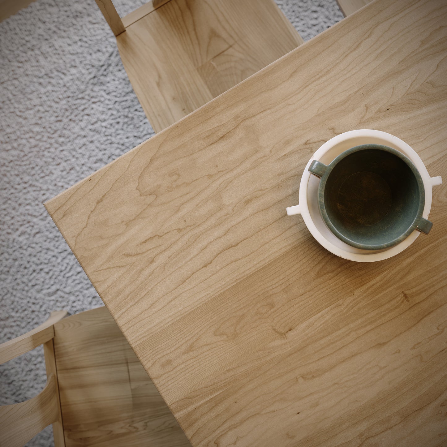 Wooden table with a green mug on a textured carpet background