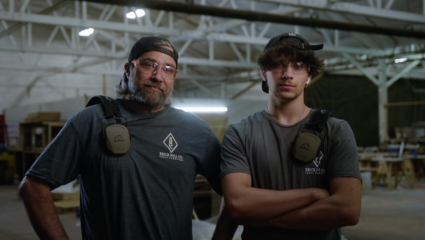 A father and son standing in a woodworking shop