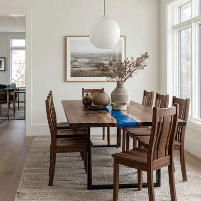 A dining room scene showing a rectangular wooden dining table with six matching wooden chairs, styled with a blue runner, ceramic vases, and a large white globe pendant light hanging above.