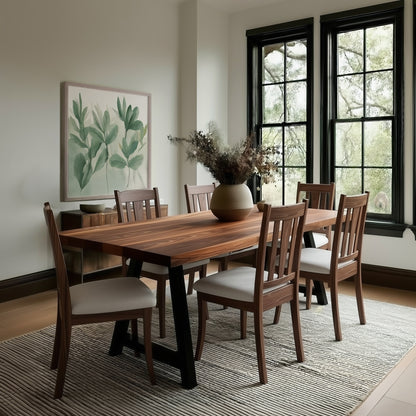 Dining room with wooden table and chairs, large windows, and a plant painting on the wall.