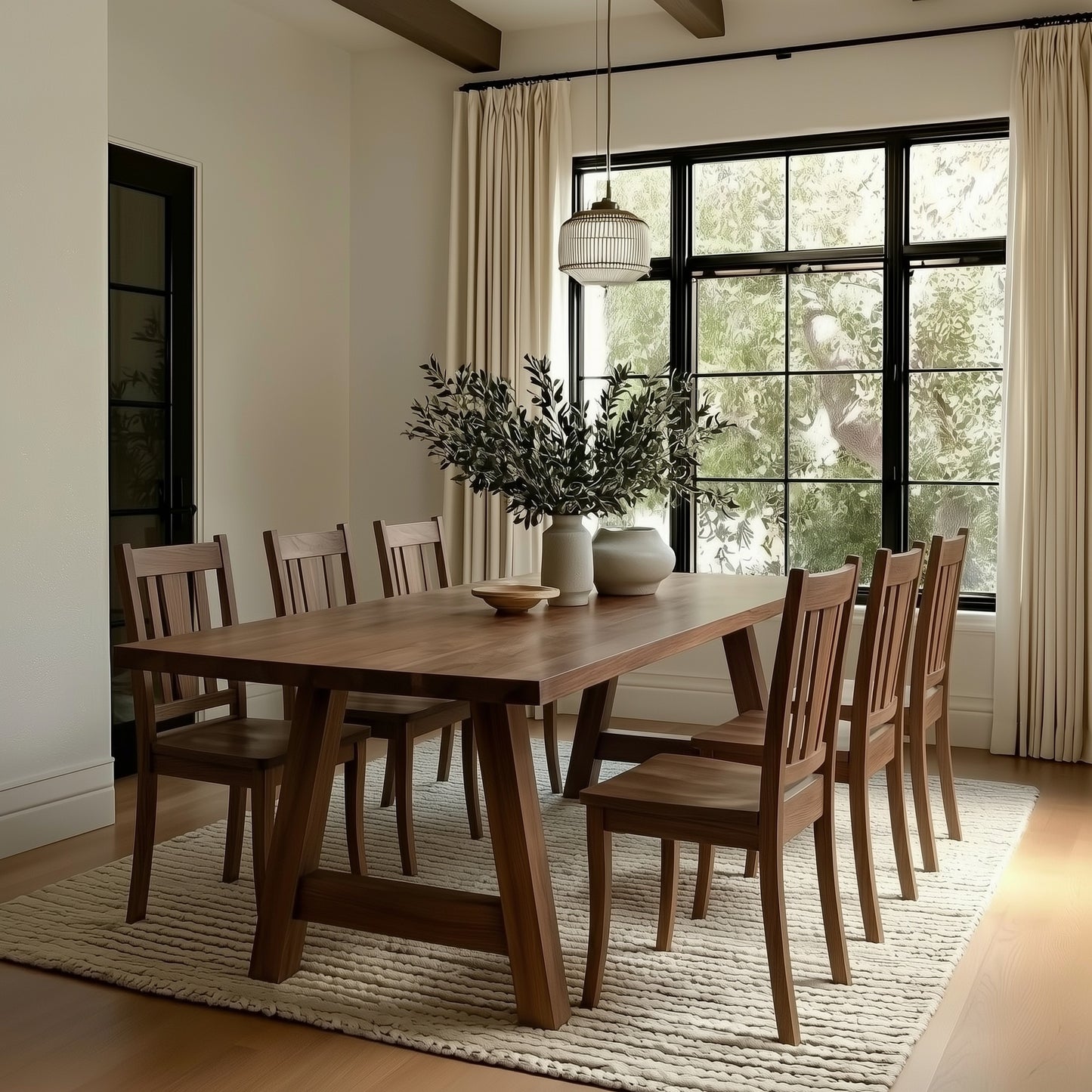 Dining room with wooden table and chairs, large window, and decorative plants.