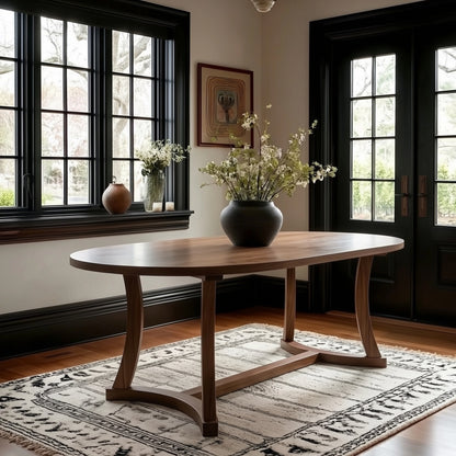 Wooden dining table with a vase of flowers in a room with large windows and a door.