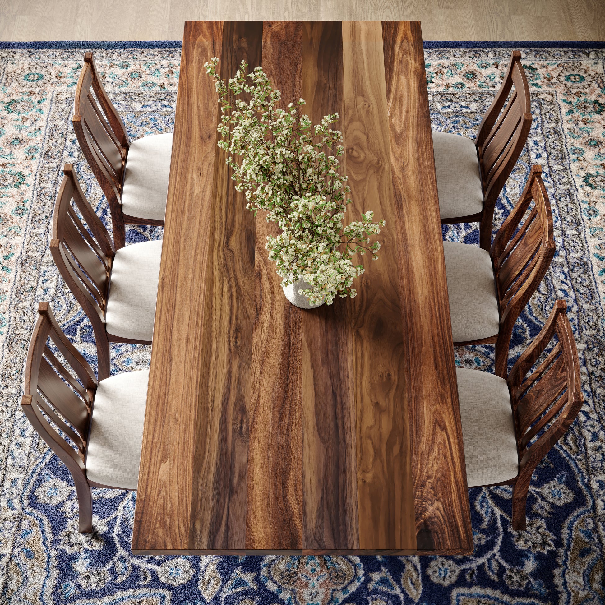 Top down view of a walnut dining table with turned wooden base featuring matching chairs in well lit dining room surrounded by large windows and a fireplace