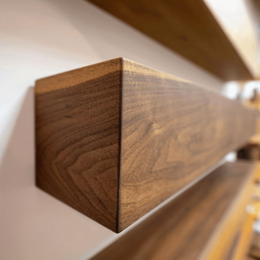 A black walnut wood mantel shelf attached to a wall, showcasing the natural grain of the wood.