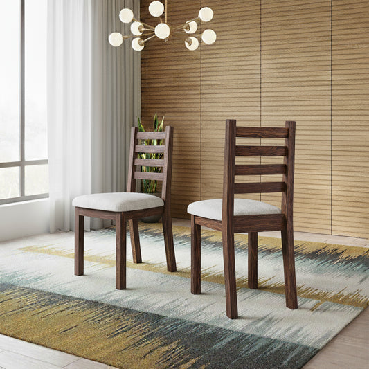 Two wooden chairs with white cushions on a patterned rug in a room with a chandelier and window.