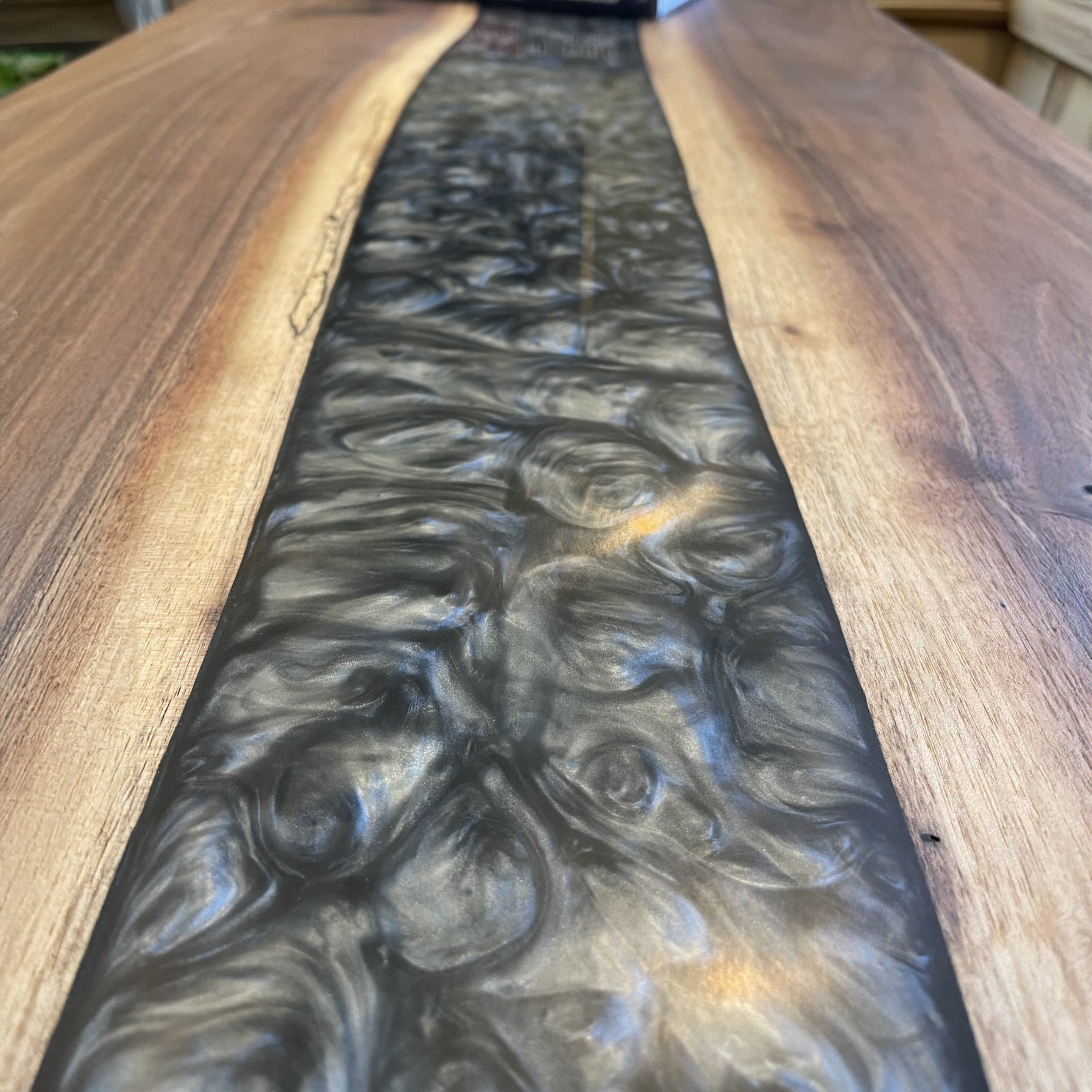 A walnut epoxy dining table with grey epoxy in a traditional living room setting