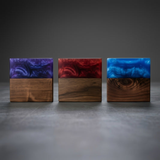 Three wooden blocks with colorful resin top layers on a dark surface