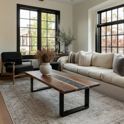 Modern living room with a beige sofa, wooden coffee table, and large windows.