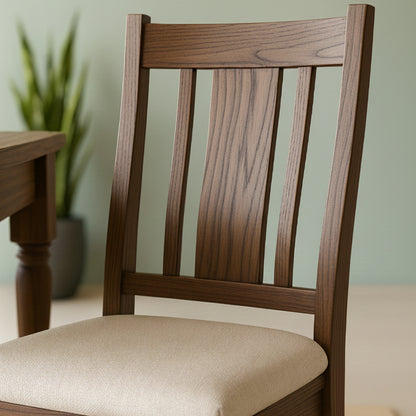 Walnut wood Finley chair with a beige cushion on a neutral background next to the end of a dining table