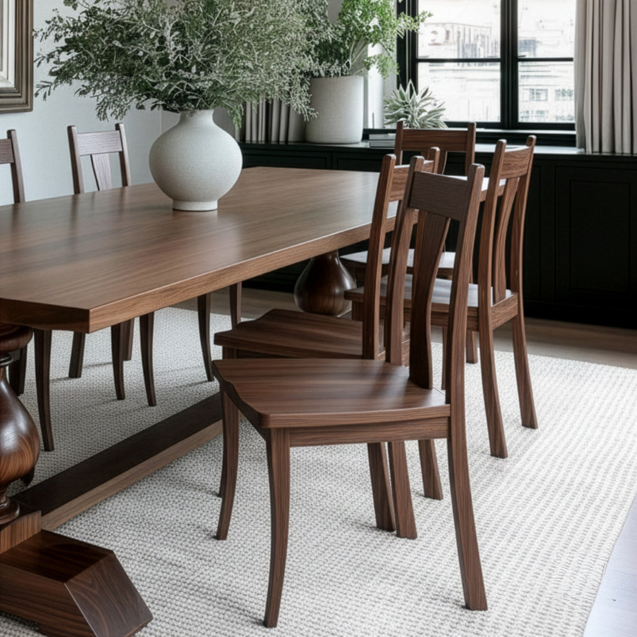 Wooden dining table with chairs in a room with large windows.