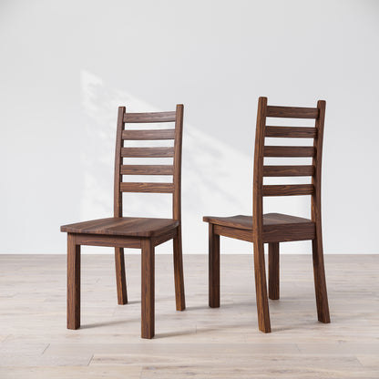 Two walnut wood Heisly dining chairs with a commercial grade finish, displayed against a white background.