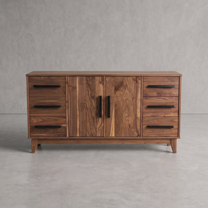 A mid-century modern wooden sideboard with a warm walnut finish, featuring two central doors with black vertical handles and four drawers on each side with black horizontal bar handles, set against a gray concrete wall and floor.