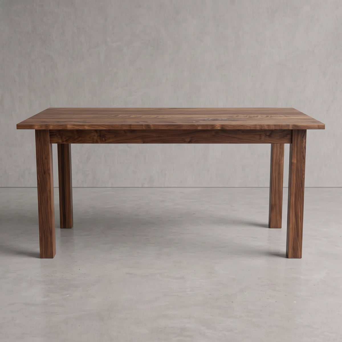 A rectangular wooden dining table with a dark brown walnut finish, featuring four sturdy legs and a thick tabletop, set against a neutral gray concrete floor and textured gray wall.