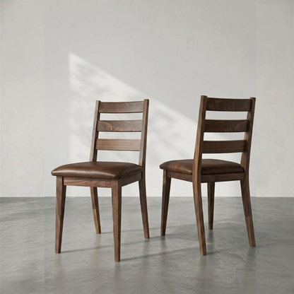 Two wooden dining chairs with brown leather seats, shown from the back in a minimalist studio setting with a gray floor and white wall.