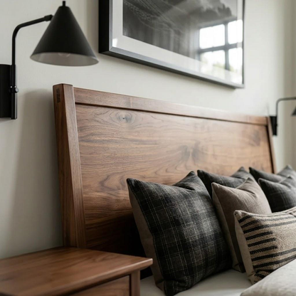 Wooden headboard with pillows and a lamp on a wall