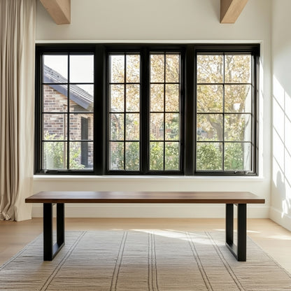 Modern interior with a wooden bench in front of large black-framed windows.