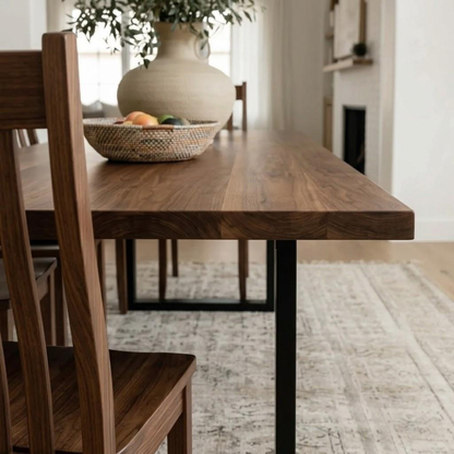 Wooden dining table with a vase and fruit on top, in a home setting.