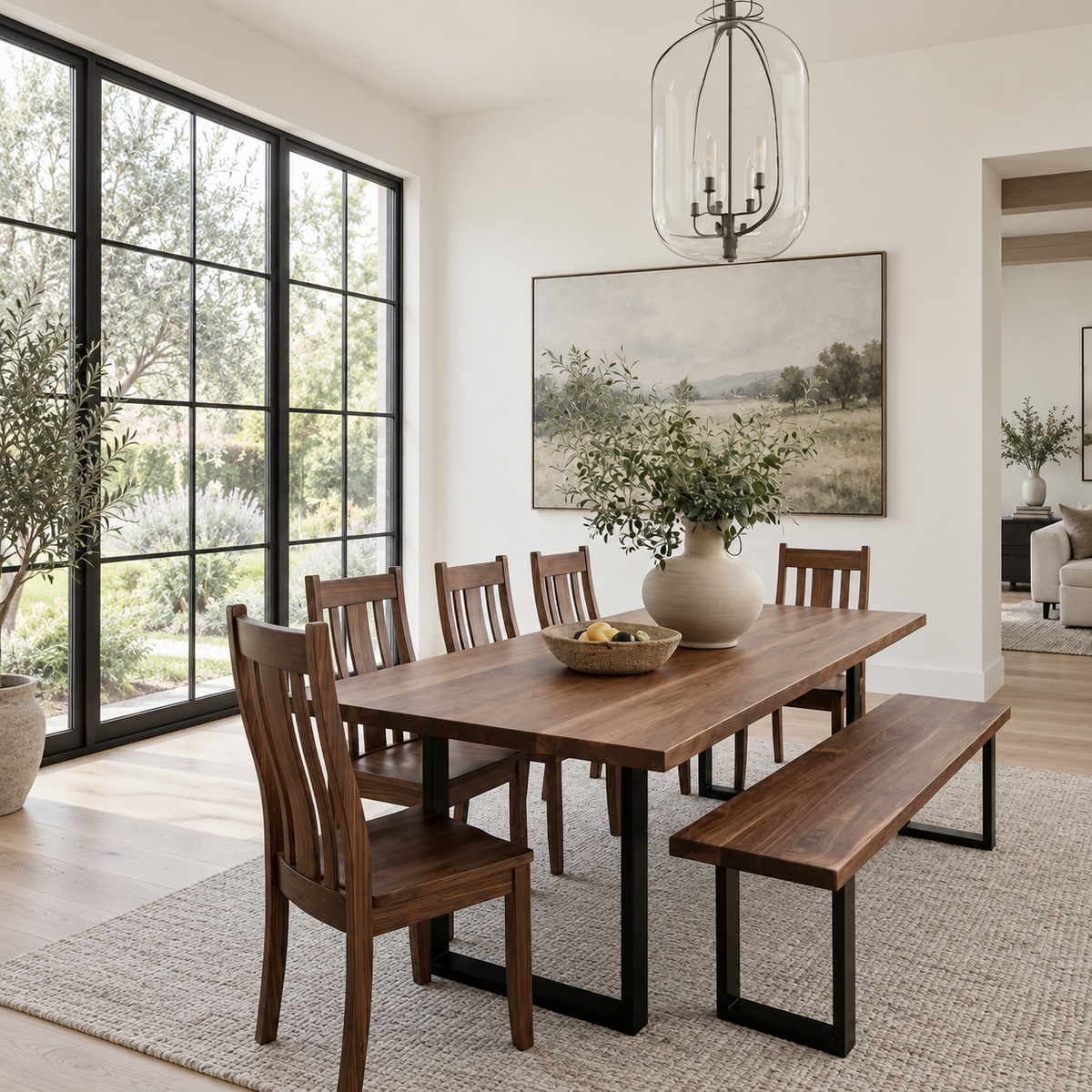 Dining room with wooden table and chairs, large windows, and a vase of flowers.