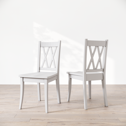 Two white wooden dining chairs with a 'Double X Back' design, placed against a neutral background.