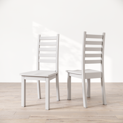 Two white wooden dining chairs with a commercial grade finish, displayed against a white background.