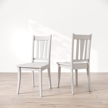 Two white wooden dining chairs with a brown finish, showcasing a slatted backrest and a solid seat, placed against a white background.
